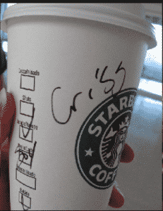 White starbucks coffee cup with logo and a handwritten name on the side held by a person