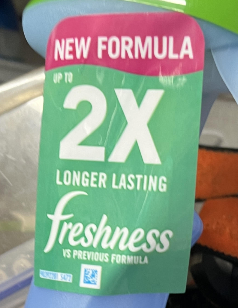 Green promotional tag reading new formula with 2x longer lasting freshness text on the label