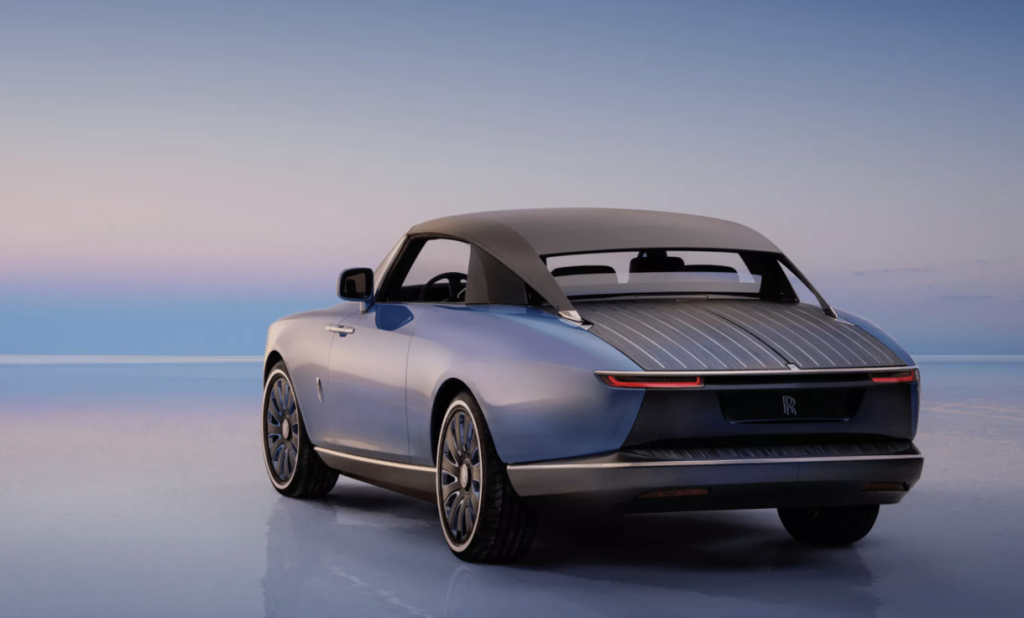 Blue rolls royce convertible photographed on a reflective salt flat at sunset rear view emphasis on the soft top and contours
