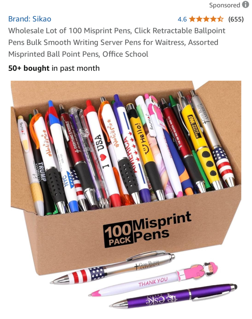 Box of 100 misprint pens with colorful designs and patriotic patterns visible inside a cardboard carton