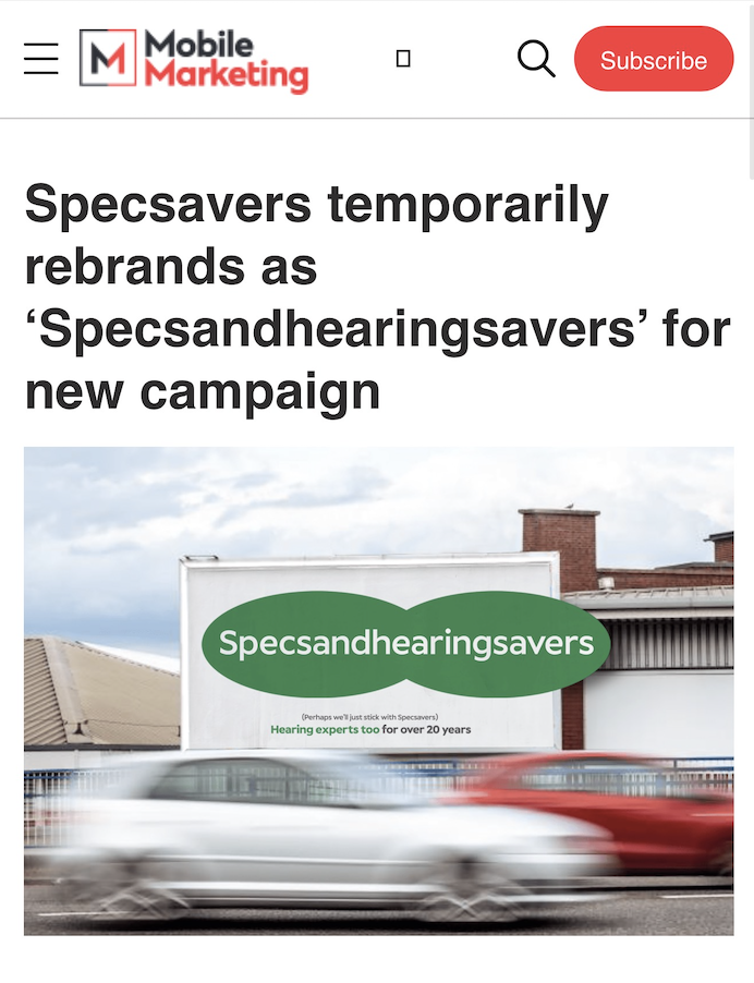 Billboard on a street showing a green specsandhearingsavers logo as blurred cars pass by illustrating the rebrand article