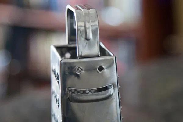 Close up of a shiny metal robot figurine with a smiling face set against a blurred indoor background