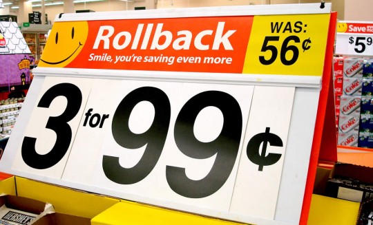 Store sale sign rollback banner with big 3 for 99¢ and was 56¢ text in a supermarket aisle