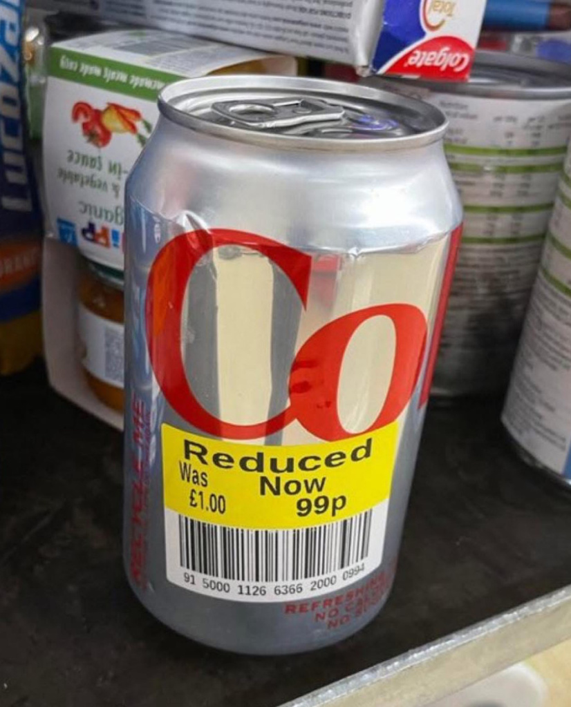Cocacola can on a store shelf with a yellow sale sticker reading reduced now 99p