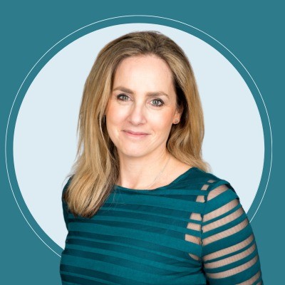 Lisa catto profile picture Professional headshot of a smiling blonde woman in a teal striped top against a light blue circular backdrop