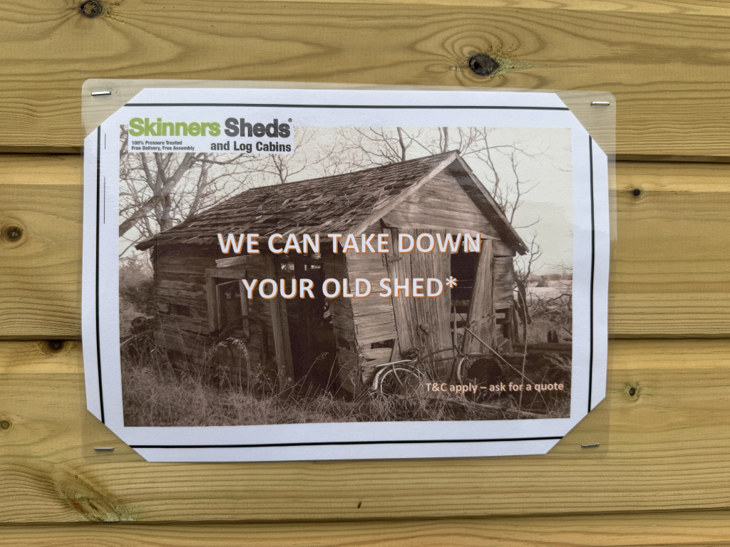 Img 9038 1 Poster advertising shed removal services on a wooden exterior wall shows an old shed image with the headline we can take down your old shed and brand skinners sheds