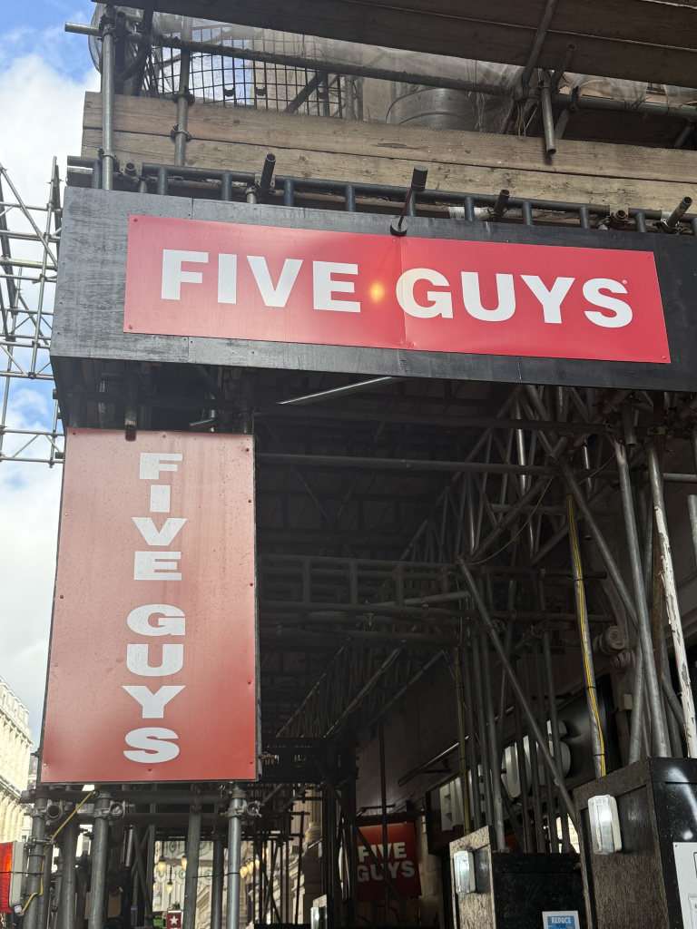 Img 9335 Red five guys sign mounted on a weathered scaffolded storefront under renovation