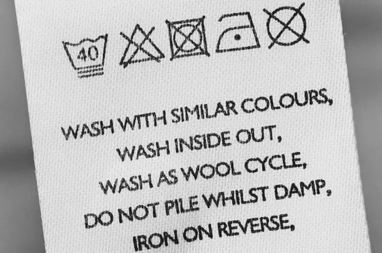 Care label showing washing instructions and symbols machine wash at 40°c do not bleach wash inside out wool cycle do not tumble dry iron on reverse