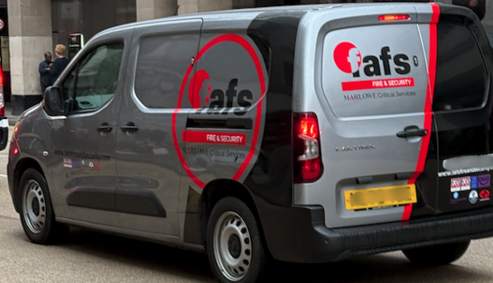 Grey security van with bright orange branding afs fire  security parked near a building rear doors and side logo visible